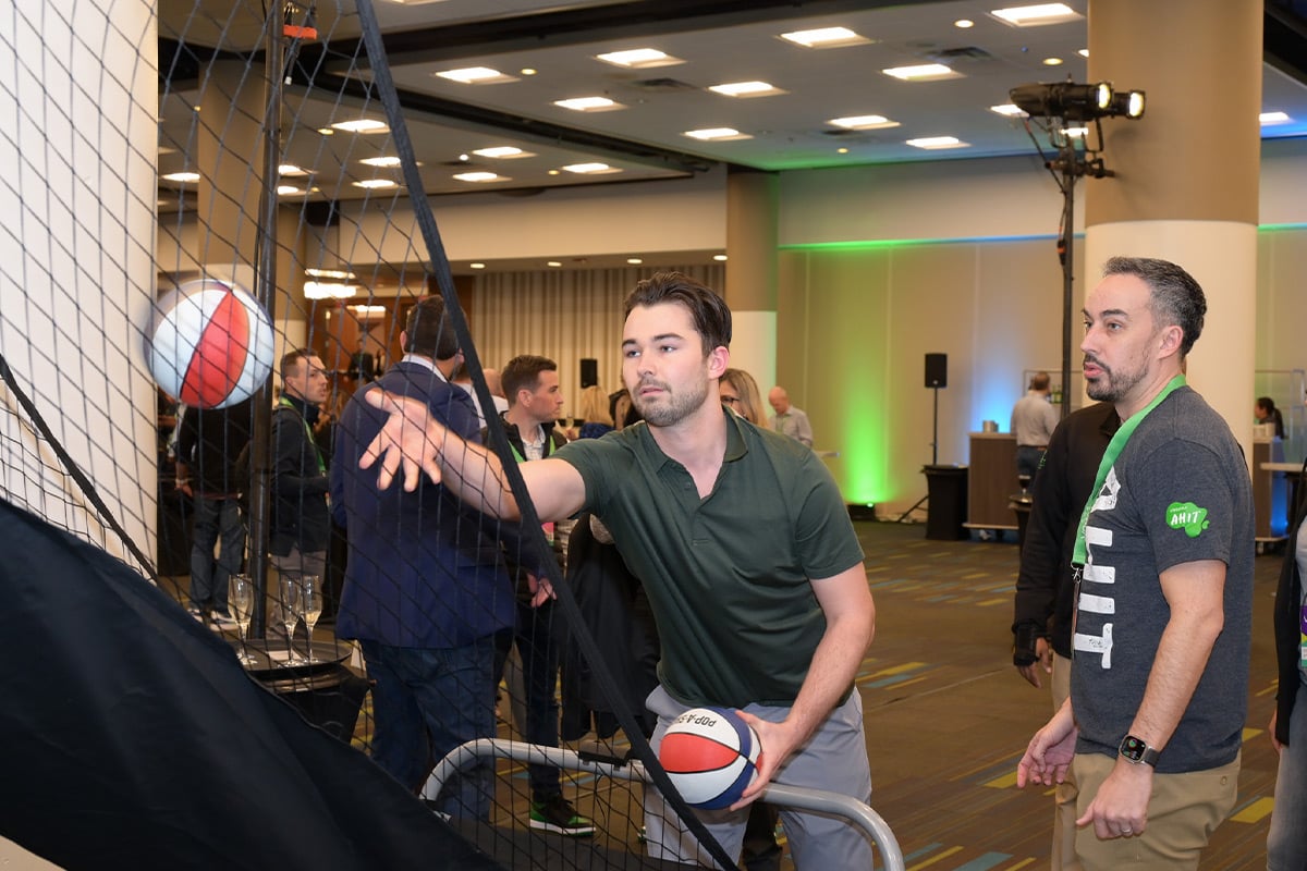 Two men playing volleyball at indoor Atlanta event with spectators
