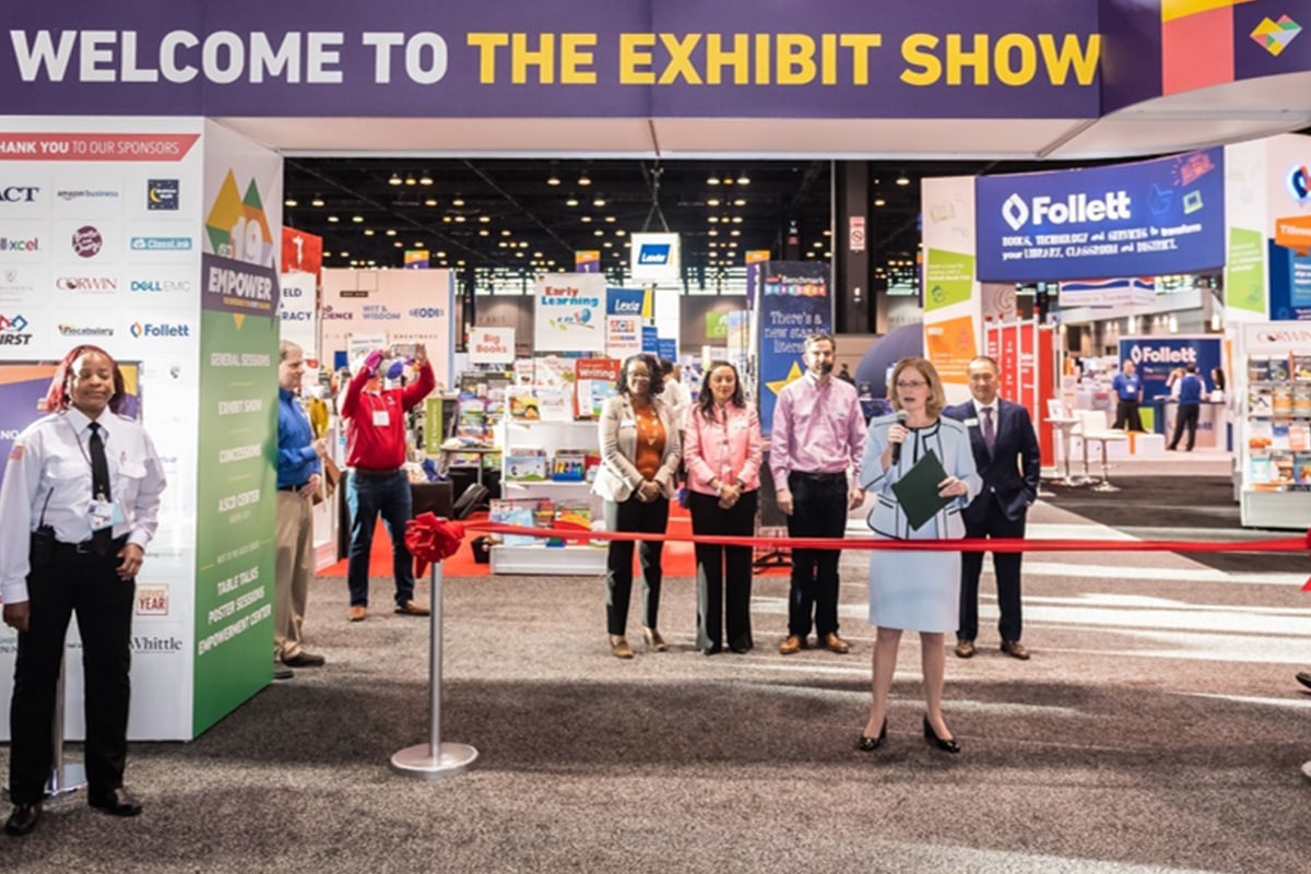 Ribbon-cutting ceremony at exhibit hall entrance with "Welcome to the Exhibit Show" sign