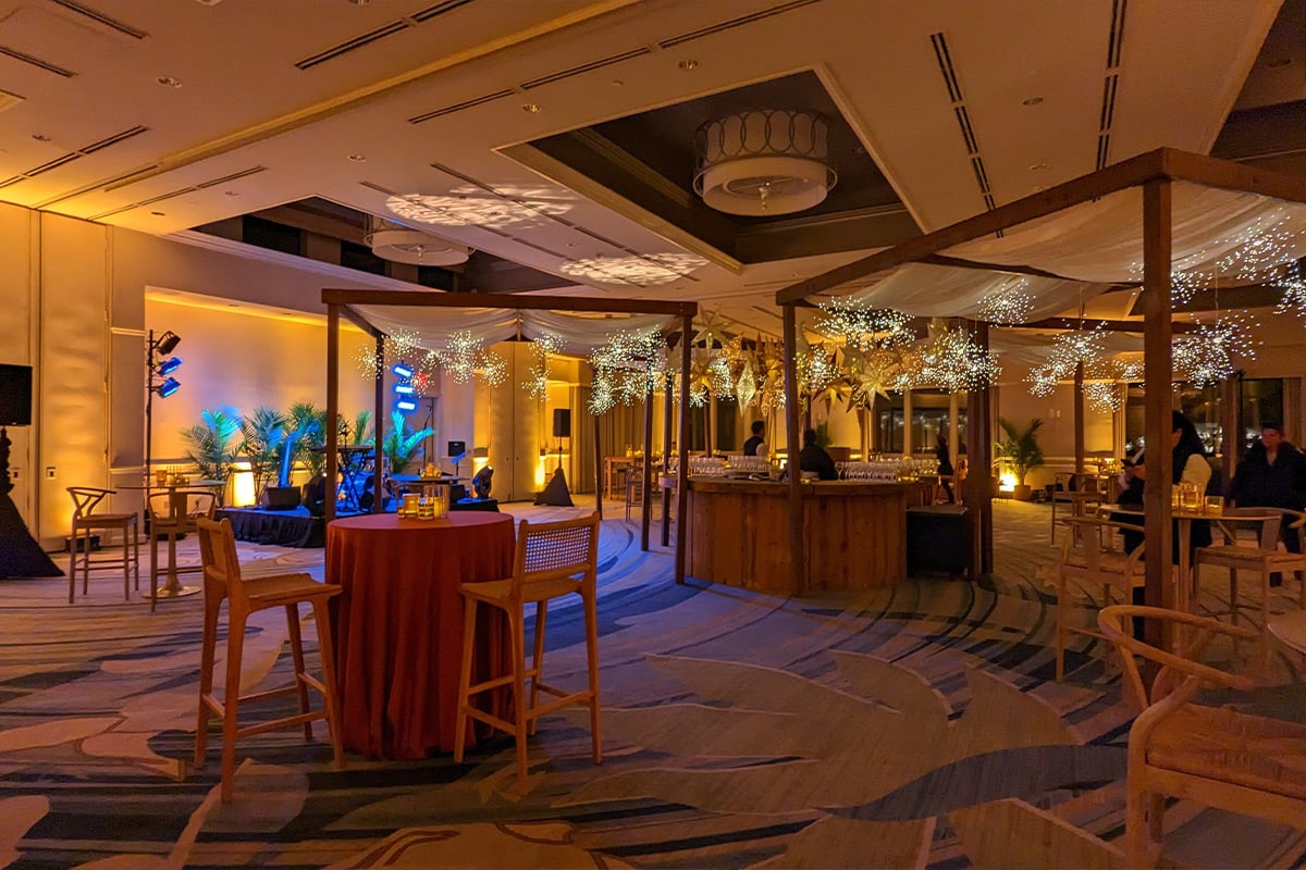 Modern hotel ballroom reception area with wooden pergola, string lights, and warm ambient lighting.