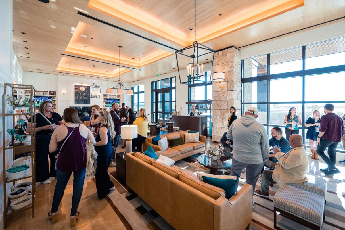 Attendees network in modern hotel lobby lounge with tan sofas and floor-to-ceiling windows.
