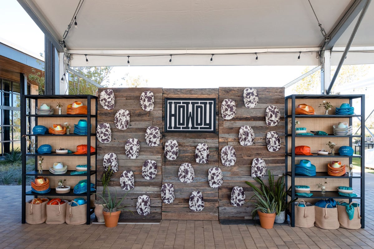 Rustic wood wall display with cowhide art and turquoise and orange pottery on flanking shelves.