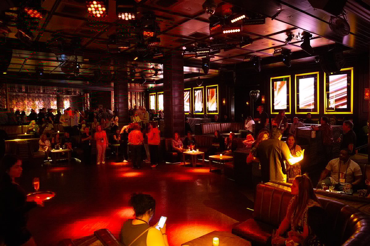 Crowd socializing in upscale lounge with red lighting and modern decor