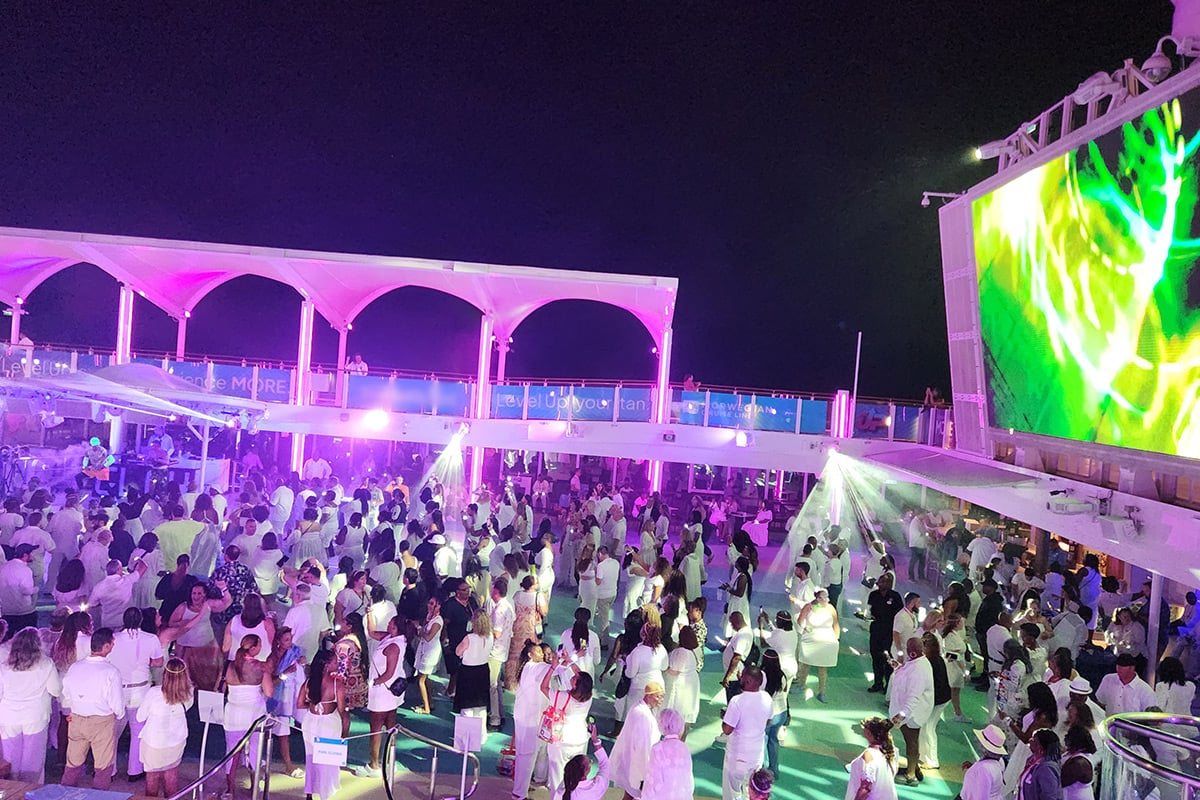 White party on cruise ship deck with large screen and purple lighting