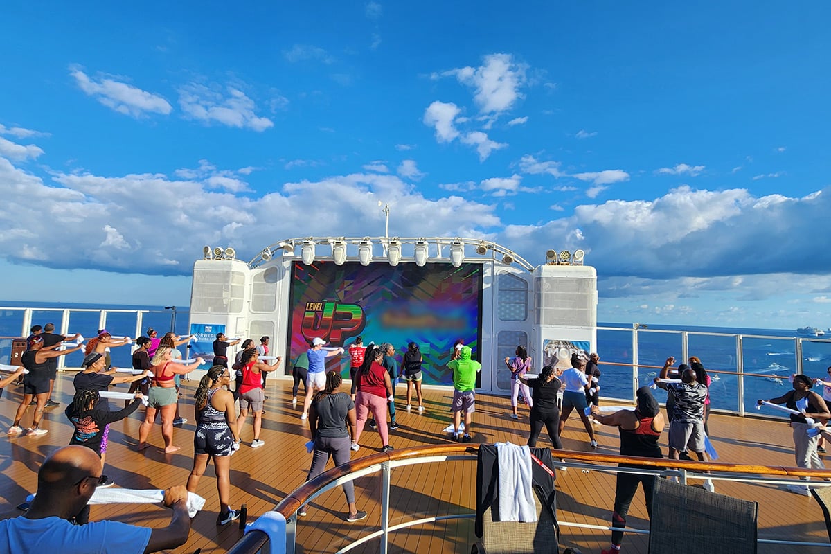 Fitness class on cruise ship deck with ocean view and blue sky
