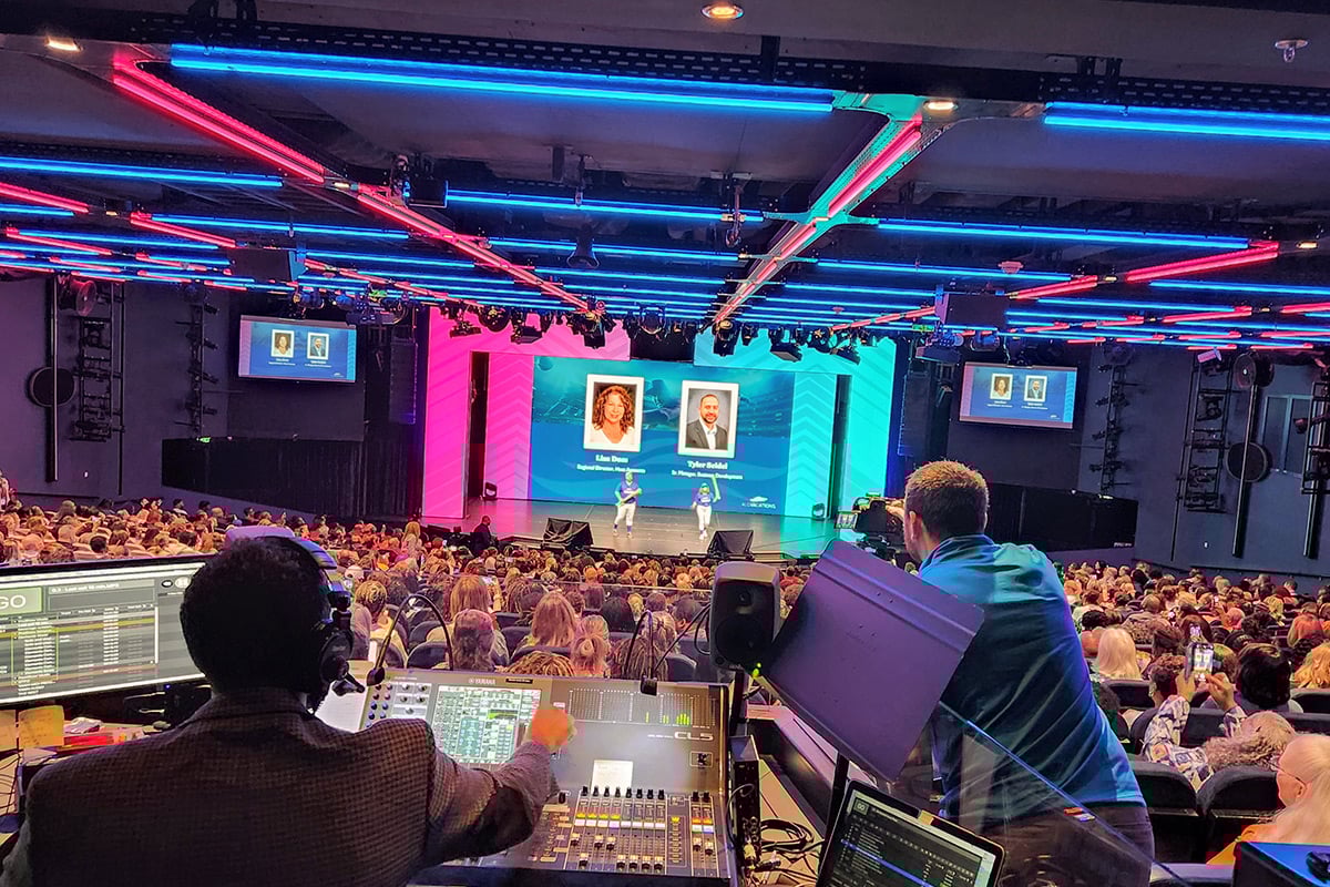 Audience watching presentation with neon lighting and screens in theater