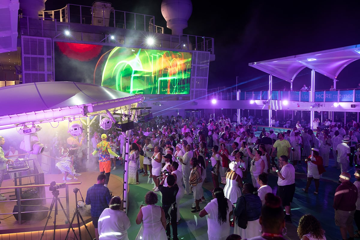 Evening party on cruise ship deck with purple lighting and large crowd
