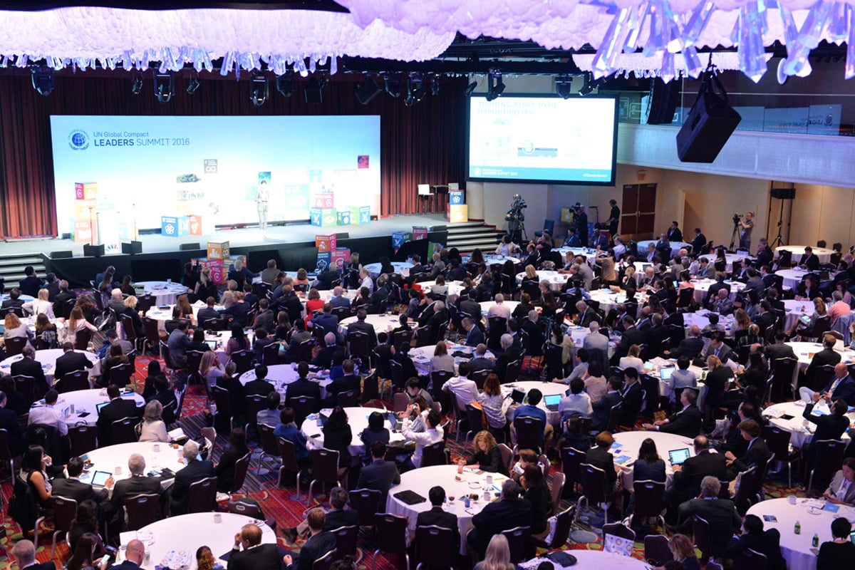 Large conference hall filled with attendees at round tables facing main stage with UN summit branding.