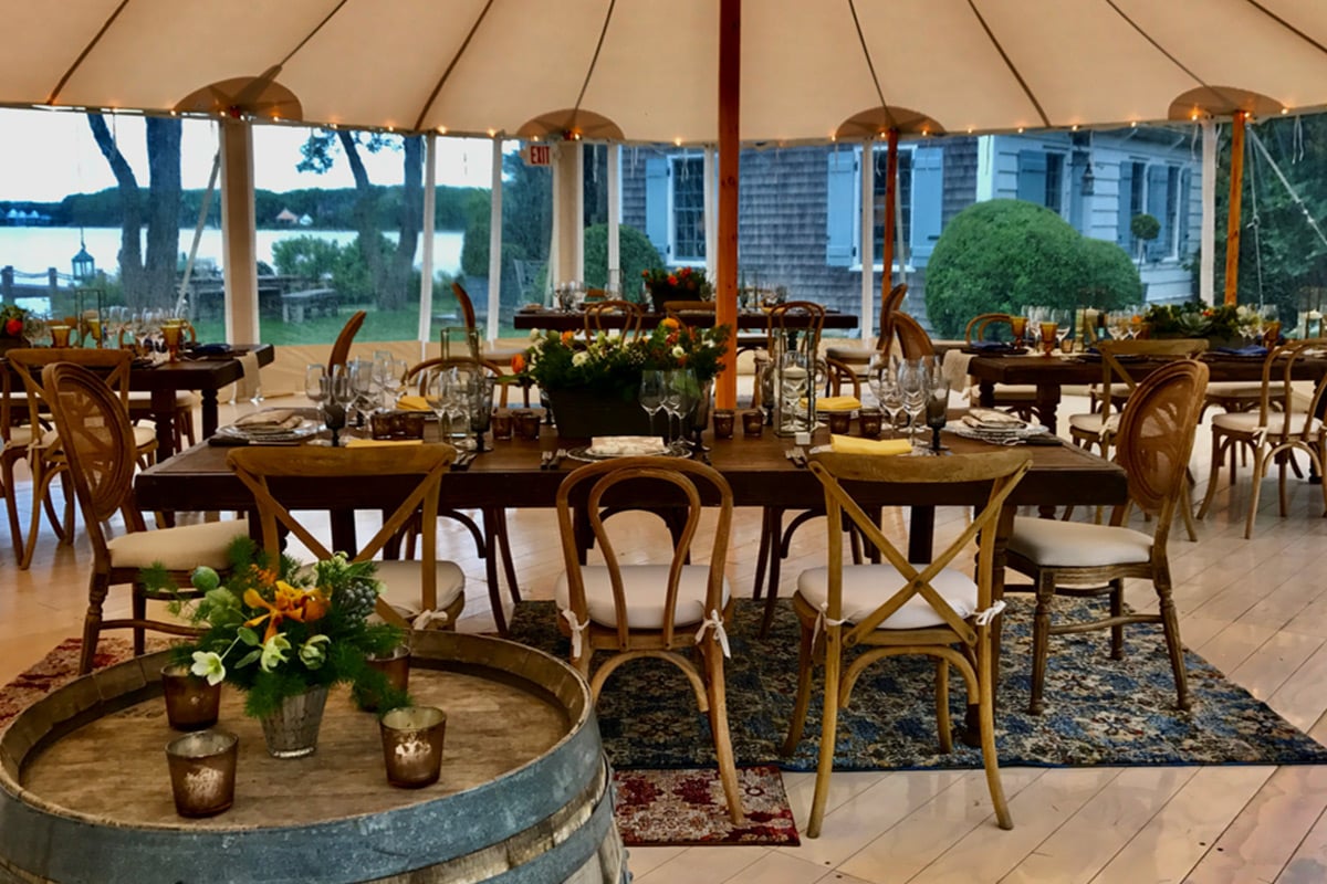Elegant tent dining setup with lake view and mixed wooden chairs