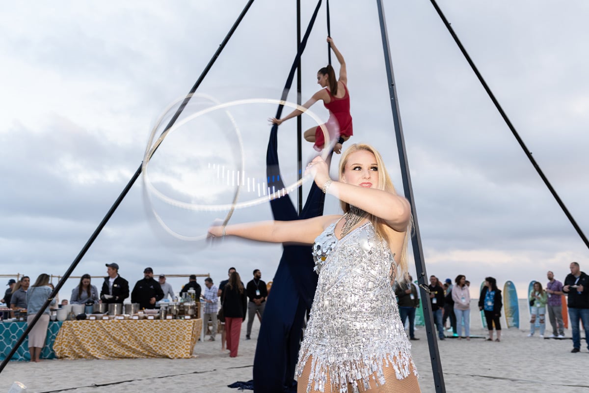 Aerial performers in silver and red costumes entertaining crowd under black tent structure